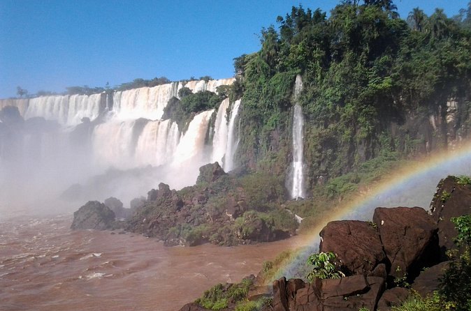 A rainbow over the brown Iguazu River below the falls